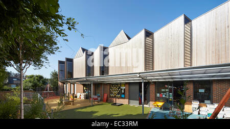 Hollymount School di Londra, Regno Unito. Architetto: Haverstock Associates LLP, 2013. Panoramica prospettiva di facciata con playgro Foto Stock