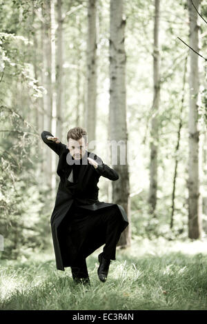 Uomo con mantello nero nella foresta Foto stock - Alamy