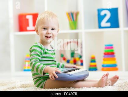 Felice piccolo bambino suonare il pianoforte giocattolo Foto Stock