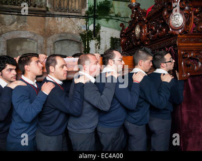 Processione del Martedì Santo la notte della settimana di Pasqua in Algeciras. I membri di fraternità indossando un pesante la figura di Gesù Foto Stock