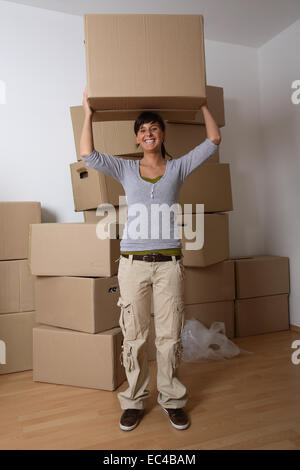 Giovane donna recante una scatola di movimentazione Foto Stock