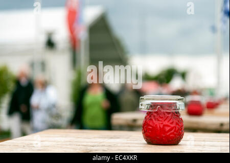 Una candela rossa e un posacenere su un tavolo Foto Stock