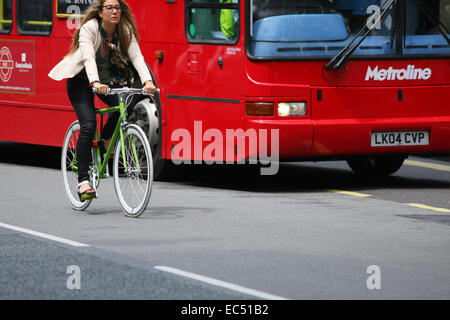 Una femmina di un ciclista che passa un autobus alla fermata dell autobus di Oxford Street, Londra Foto Stock