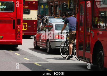 Un ciclista in attesa per il trasferimento del traffico in Oxford Street, Londra Foto Stock