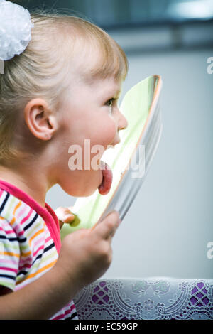 A 4 anni ragazza leccare una piastra Foto Stock