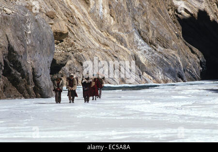 Ladakh sul fiume di ghiaccio. Una spedizione attraversa il ghiaccio. Regione montagnosa. Le figure a piedi in una linea. Foto Stock