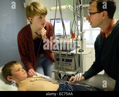 Studente di medicina Isabel Hillmann (L) con il medico di paese Stephan Fuchs esaminare un anno sette old boy con un elettrocardiogramma al medico di paese in pratica in Wettin, Germania, 27 novembre 2014. Lo studente (3° semestre), che gli studi presso la scuola di medicina a Martin Luther University di Halle, è uno dei 68 studenti di medicina scelto per prendere parte alla nuova imposta corso 'Classe Medicie generale' a prepararsi ad essere una casa e medico di paese, che è un periodo supplementare di cinque anni di studio. Il progetto didattico istituito nel 2011 è stato insignito del "paese tedesco di idee" premio. Foto: WALTRAUD GRUBITZSCH/dpa Foto Stock