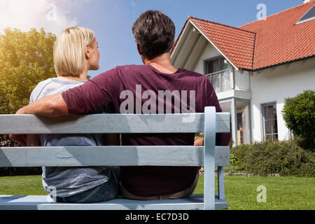 Vista posteriore della coppia matura seduta sul banco in giardino Foto Stock