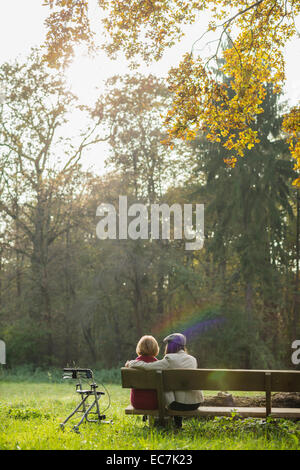 Donna Senior e nipote seduta su una panchina nel parco, vista posteriore Foto Stock