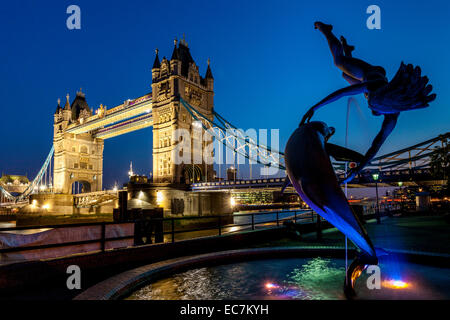 Ragazza con una fontana dei Delfini e il Tower Bridge di Londra, Inghilterra Foto Stock