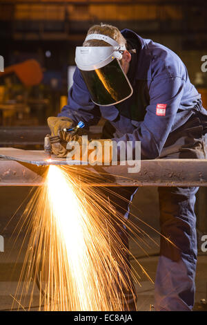 Un artigiano di indossare dispositivi di protezione individuale durante il lavoro con acciaio e utensili a mano in un laboratorio industriale nel Regno Unito Foto Stock