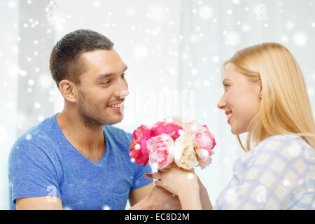 Uomo sorridente dando ragazza fiori a casa Foto Stock