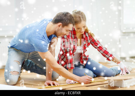 Coppia sorridente misurando il pavimento in legno Foto Stock