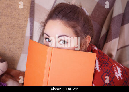 Carino ragazza sul divano con un libro in mano Foto Stock