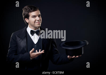 Il mago che mostra i trucchi con top hat isolato su sfondo scuro Foto Stock