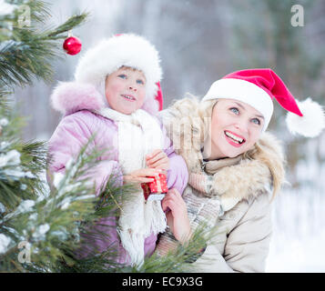 La famiglia felice la madre e il bambino decorare albero di natale per esterno Foto Stock