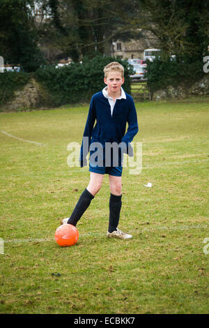 Ragazzo giocando a calcio a scuola Foto Stock