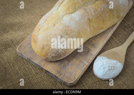 Il pane e il cucchiaio riempito con farina di pane di bordo su sfondo di tela Foto Stock