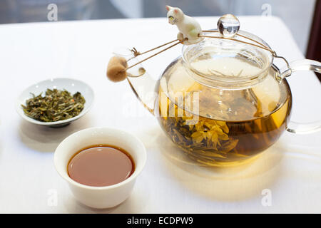 Tazza di Tè sfuso tè a foglia, e vetro teiera sulla tovaglia bianca Foto Stock