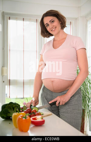 Donna incinta a preparare il pranzo insalata di cibo sano Foto Stock