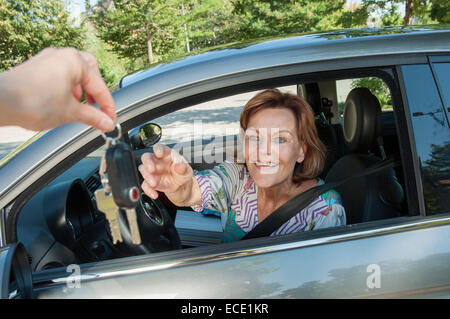 Senior donna chiave di ricezione per la nuova vettura Foto Stock