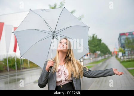 Donna anticipazione tempesta protezione ombrello Foto Stock