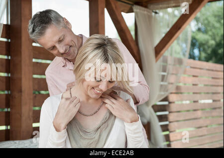 Giovane donna felice mettendo a collana Foto Stock