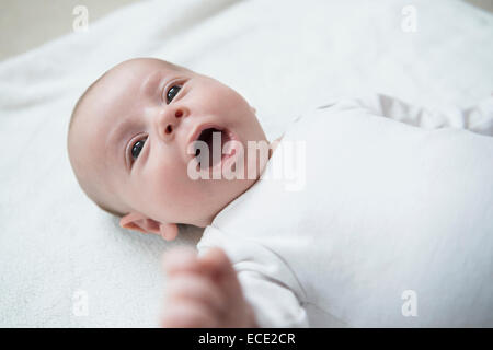 Baby boy sdraiato sul letto con la bocca aperta Foto Stock