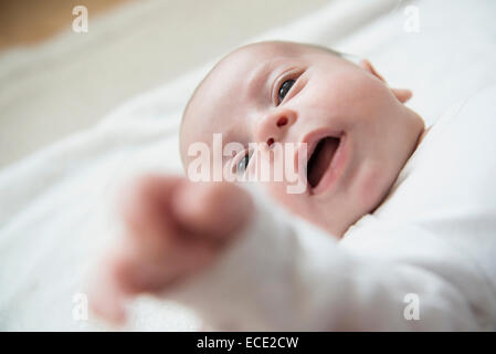 Baby boy sdraiato sul letto con la bocca aperta Foto Stock