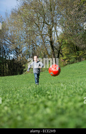 Piccolo Ragazzo in esecuzione prato calcio giocando Foto Stock