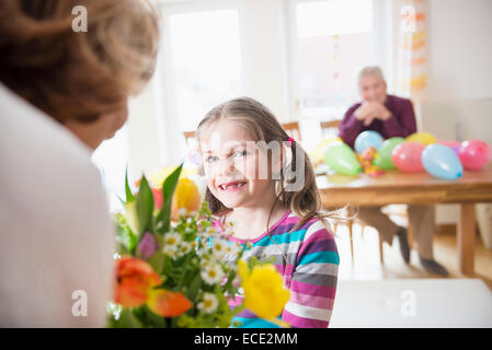 La nipote mano sul mazzo di fiori alla sua nonna mentre nonno in background Foto Stock