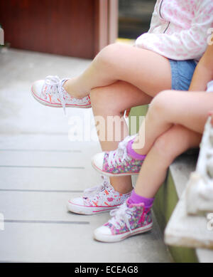Due ragazze che si siedono fianco a fianco Foto Stock