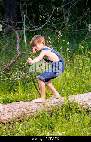 Giovane ragazzo su albero caduto con arco e frecce Foto Stock