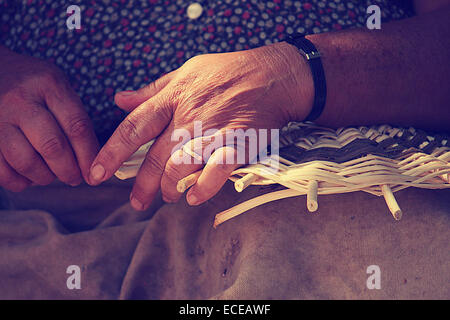 Close up di mani femminili cestello di tessitura Foto Stock