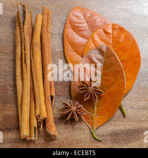 Ancora in vita di bastoncini di cannella e chiodi di garofano di anice e foglie di autunno disposto su una superficie di legno Foto Stock