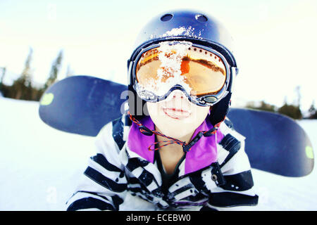 Ritratto di ragazzo sdraiato nella neve con uno snowboard Foto Stock