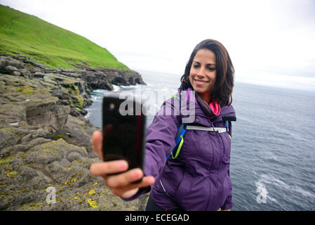 Giovane donna prende un selfie in Trøllanesi, Kalsoy, Isole Faerøer Foto Stock