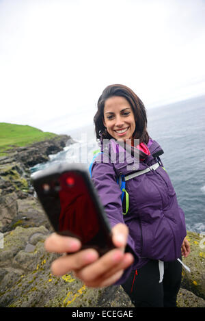 Giovane donna prende un selfie in Trøllanesi, Kalsoy, Isole Faerøer Foto Stock