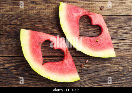 Due fette di cocomero con taglio a forma di cuore su sfondo di legno. Vista superiore Foto Stock