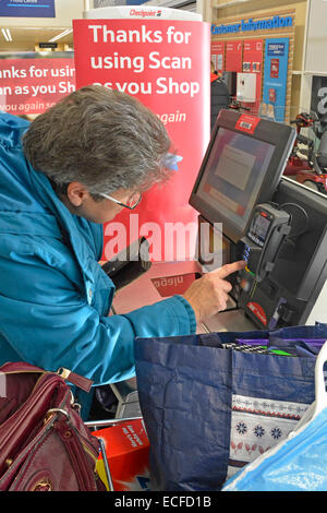 Senior supermarket shopper alla scansione self-service come si acquista checkout fino a entrare carta di credito per pagare scanner manuale shopping Londra Inghilterra UK Foto Stock