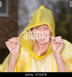 Donna che ride indossando un poncho di plastica durante una doccia di pioggia Foto Stock