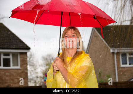 Donna che mantiene il suo red ombrello aperto durante un acquazzone pesante di pioggia Foto Stock