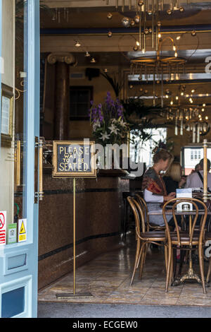 Si prega di attendere di essere seduto legge il segno al Grand Cafe su High Street, Oxford che sostiene di essere il primo coffee house i Foto Stock