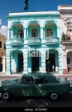 Un'auto d'epoca passa un esempio colorato di architettura coloniale spagnola restaurata sul Prado (Paseo de Marti) a l'Avana Cuba Foto Stock