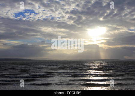 Solent, Hampshire, Regno Unito. Xiv Dic, 2014. Lepe sul Solent, Hampshire, Regno Unito. Il sole del pomeriggio si rompe attraverso le nuvole sopra l'Isola di Wight, sopra le acque burrascose del Solent agitati fino dai forti venti che soffiano lungo la costa sud dell'Inghilterra di oggi. Credito: Julia Gavin UK/Alamy Live News Foto Stock