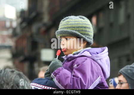 Boston, Massachusetts, USA. 13 dicembre, 2014. Un bambino piccolo con un lecca-lecca siede su un adulto di spalle durante i milioni marzo rally a Boston, Massachusetts, USA. La protesta, simili a quelli di altre città in tutto il territorio degli Stati Uniti in questo giorno, è in risposta ai recenti grand jury verdetti non incriminante i poliziotti che hanno ucciso disarmato gli uomini neri Michael Brown e Eric Garner, e per le persistenti problemi del razzismo e della polizia brutalità. Credito: Susan Pease/Alamy Live News Foto Stock