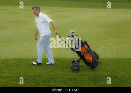 L'uomo tirando carrello da golf Foto Stock