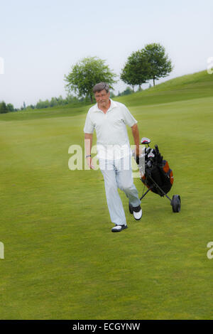 L'uomo tirando carrello da golf Foto Stock