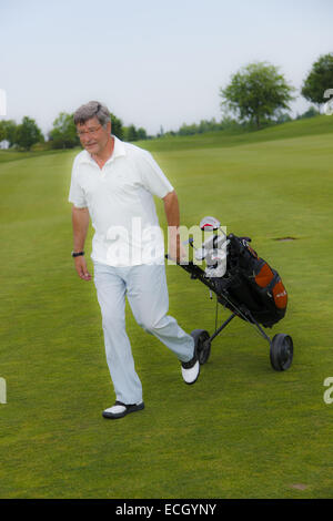 L'uomo tirando carrello da golf Foto Stock