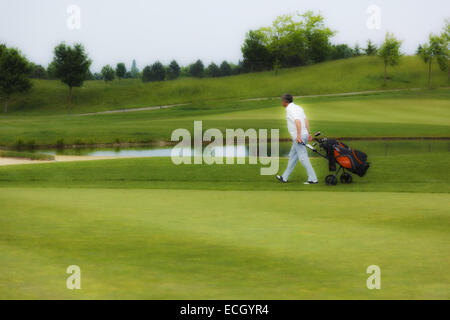 L'uomo tirando carrello da golf Foto Stock